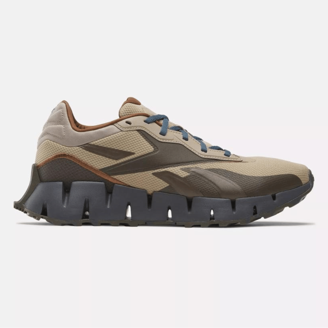 A pair of beige and brown trail running shoes with a rugged sole and blue laces.