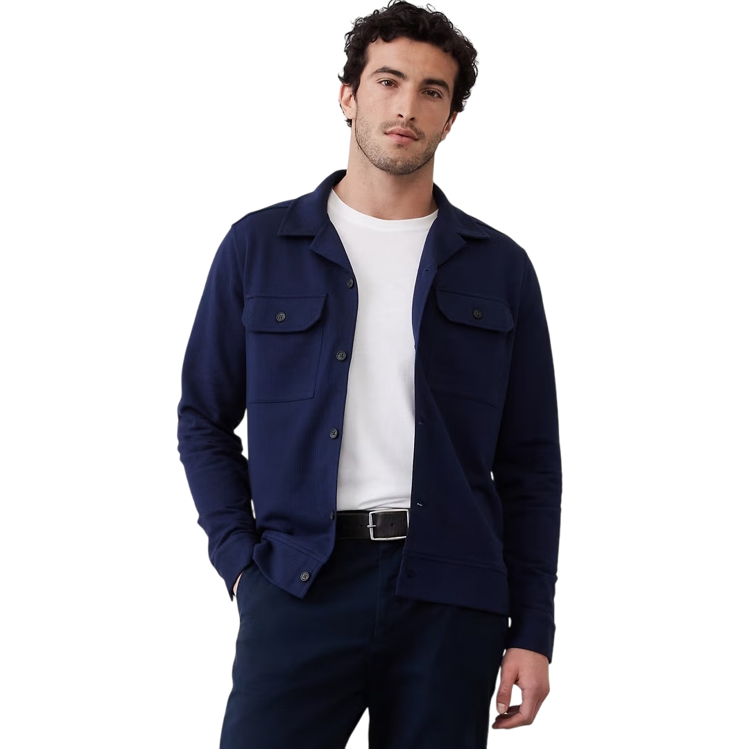 Man wearing a navy button-up overshirt with flap pockets over a white t-shirt, paired with dark pants and a black belt.