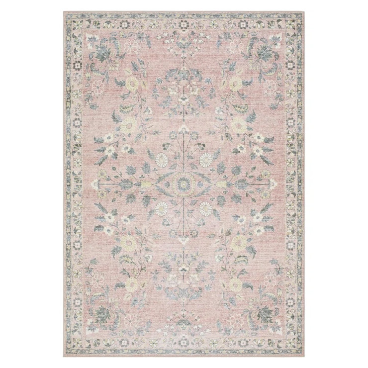 The Langley Street Washable Floral Rug features a traditional floral pattern with a soft, vintage look, primarily in muted pink and green tones. The intricate design is bordered and symmetrical, offering a classic aesthetic.