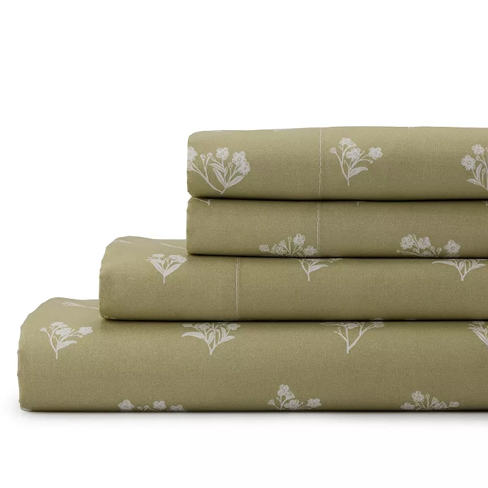 A stack of olive green bed sheets featuring a white floral pattern.