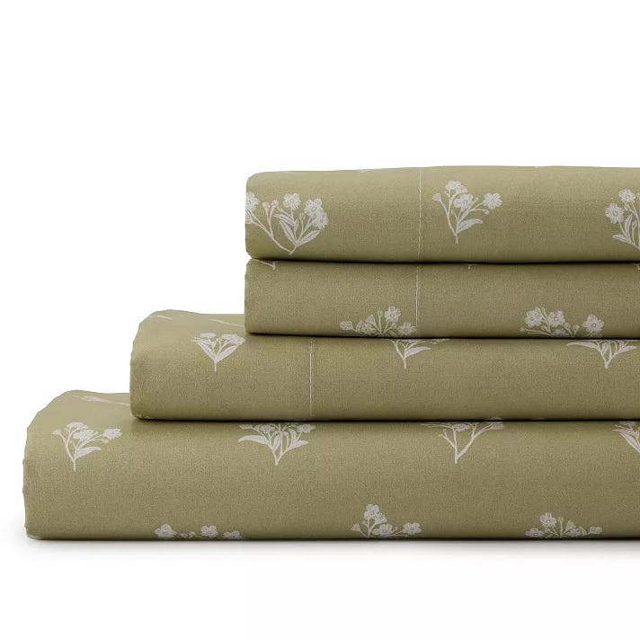 A stack of olive green bed sheets featuring a white floral pattern.