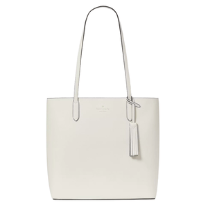 A white leather tote bag with long handles, featuring a tassel accent and subtle branding near the top.