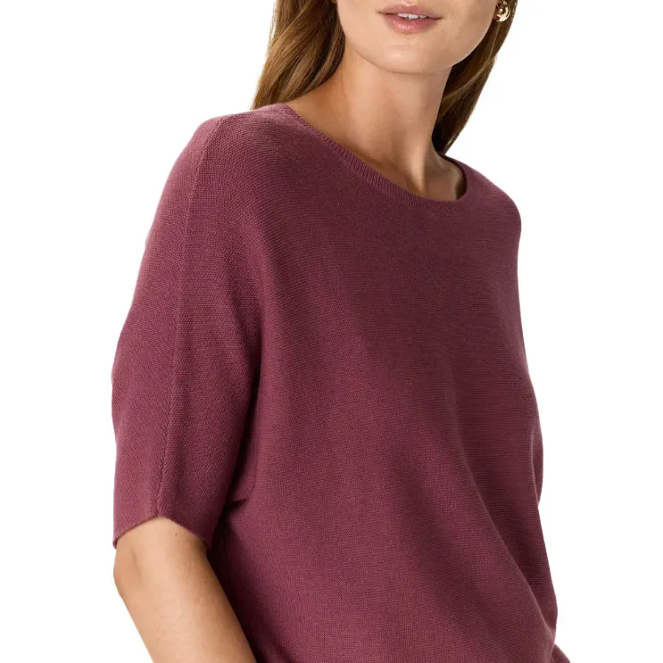 A woman is wearing a short-sleeve, maroon knit top.