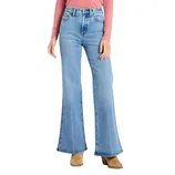 A person is wearing light blue high-waisted, flare-leg jeans with brown heeled boots, paired with a long-sleeve pink top.