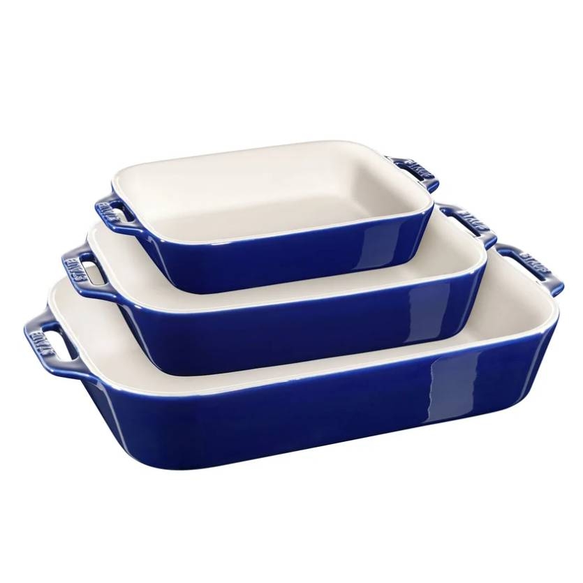 Staub 3-piece rectangular baking dish set in deep blue features three stackable dishes with handles; sizes include small, medium, and large. The dishes have a white interior designed for even cooking and easy cleaning.