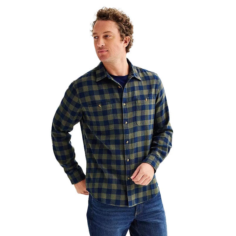 A man is wearing a long-sleeve, blue and green checkered flannel shirt paired with jeans.