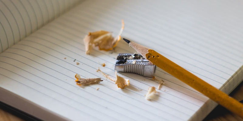 a pencil and a pencil sharpener with shavings on a piece of notebook paper