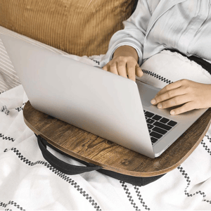 A wooden laptop table with a built-in handle. It provides a stable surface for using a laptop on a bed or couch, featuring a cushioned base for comfort and support.