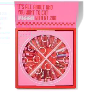 A pink and red pizza box contains JoyBright lip glosses arranged in a pizza slice pattern. The message inside the lid reads, \“It's all about who you want to eat pizza with at 2 am.\“