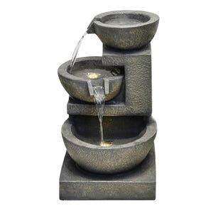 A tiered tabletop fountain with three bowls featuring flowing water illuminated by LED lights. The design showcases a minimalist and rustic stone-like texture.