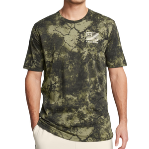 The Under Armour Freedom Shirt features a green and black camo-style pattern with a small American flag and \“FREEDOM\“ text on the chest. It's a short-sleeve, casual T-shirt.