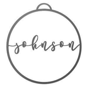 A round metal ornament features the name \“Johnson\“ in cursive script, centered within the circle, with a small loop at the top for hanging.