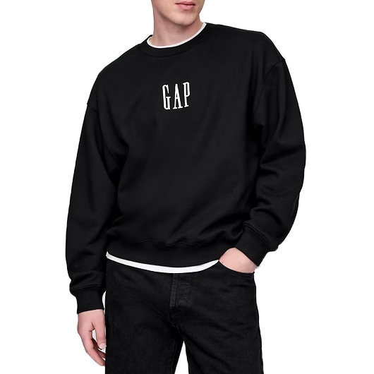 A person wearing a black GAP sweatshirt with a white logo on the front, paired with black pants.
