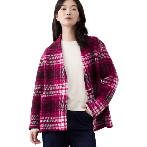 A person is wearing a bold pink plaid jacket over a cream sweater paired with dark jeans.