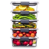 Stacked clear glass food containers with various vegetables and fruits, including lemons, green beans, zucchini, and radishes.
