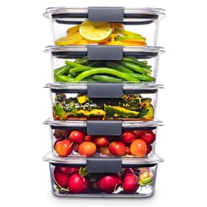 Stacked clear glass food containers with various vegetables and fruits, including lemons, green beans, zucchini, and radishes.