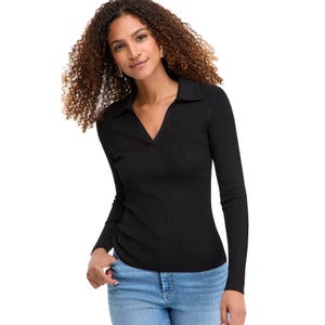 A woman is wearing a ribbed black long-sleeve top with a V-neck and collar, paired with light blue jeans.