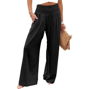 Black high-waisted wide-leg pants with a smocked waistband, paired with a straw clutch.