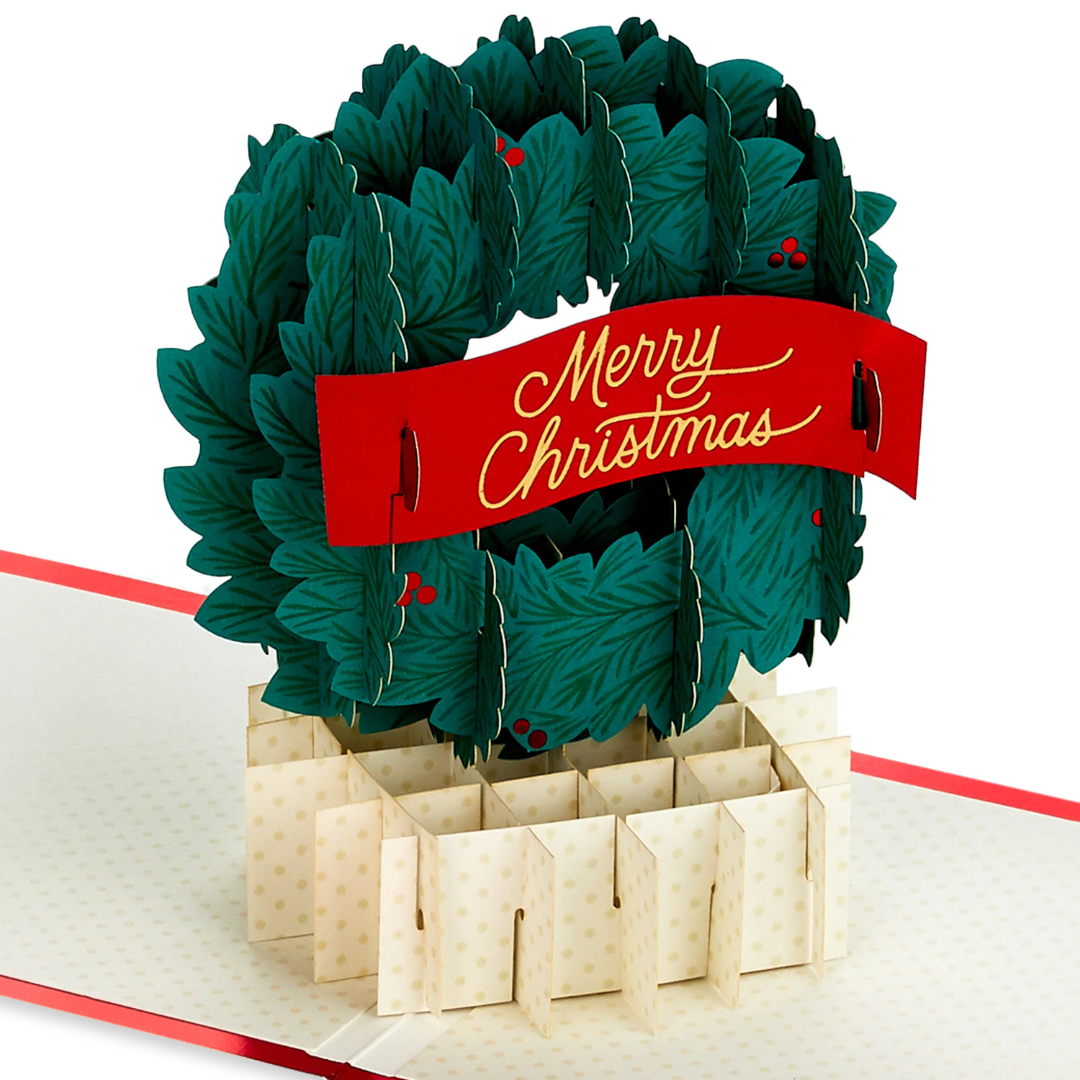 Pop-up Christmas card featuring a 3D wreath with a \“Merry Christmas\“ banner.