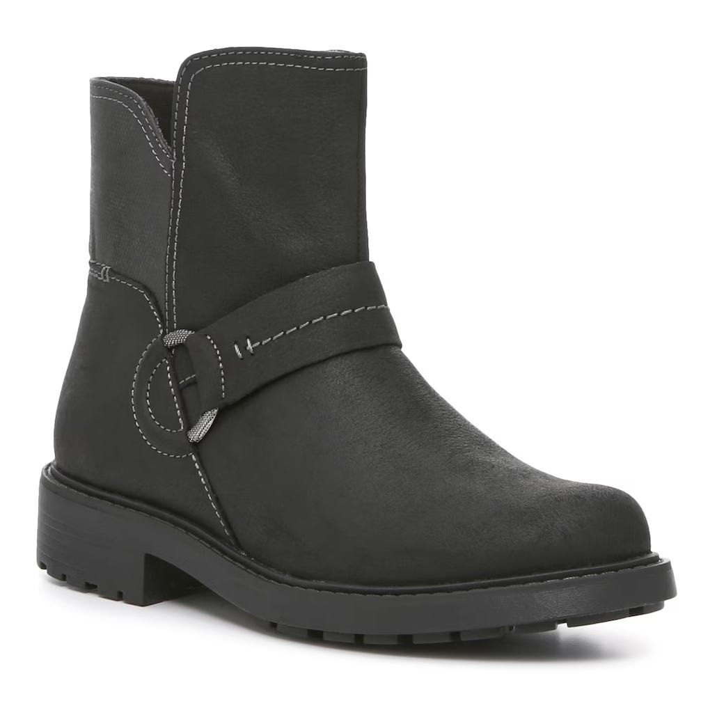 A pair of black Clarks ankle boots featuring a side buckle strap and visible stitching details, with a low, block heel and round toe.