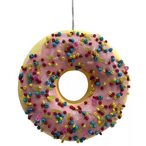 A donut ornament with pink icing and colorful sprinkles, featuring a hanging loop.