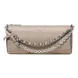 A beige Kate Spade New York clutch bag featuring a chain handle with a ribbon and charm detail.