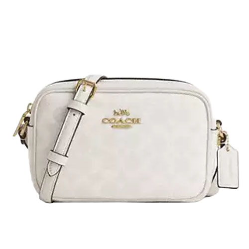 A white Coach camera bag with a gold logo and adjustable shoulder strap, featuring a small tag on the side.