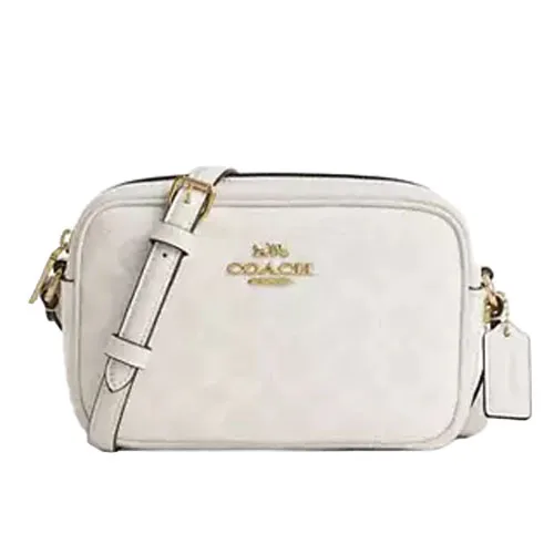 A white Coach camera bag with a gold logo and adjustable shoulder strap, featuring a small tag on the side.