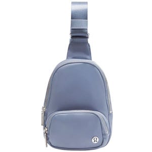 A small, light blue sling bag with a single adjustable strap and multiple zippered compartments, featuring a logo emblem on the front.