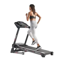 A person is running on a treadmill, wearing fitness attire, while a large screen displays an interactive workout. A smartphone is shown, illustrating connectivity features.