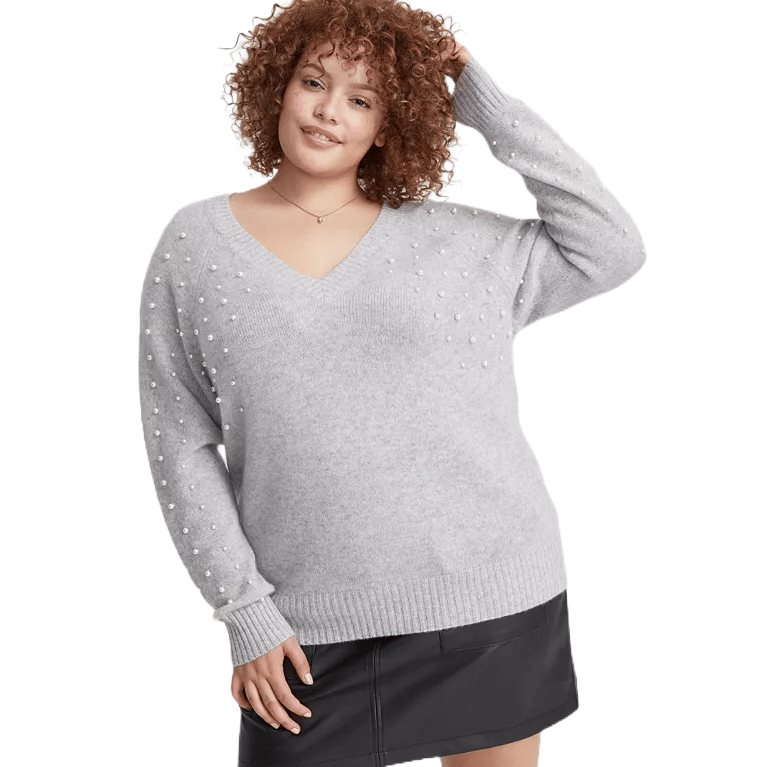 Charter Club Cashmere Sweaters feature a gray, V-neck design adorned with small, evenly spaced pearls, offering a chic and elegant look. The sweater has a ribbed hem and cuffs, paired with a black skirt.