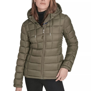 A woman is wearing an olive green puffer jacket with a hood and zipper closure, paired with black pants.