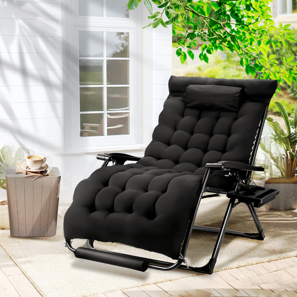 A black cushioned metal chaise lounge with an adjustable backrest and fold-out side table is set on an outdoor patio.