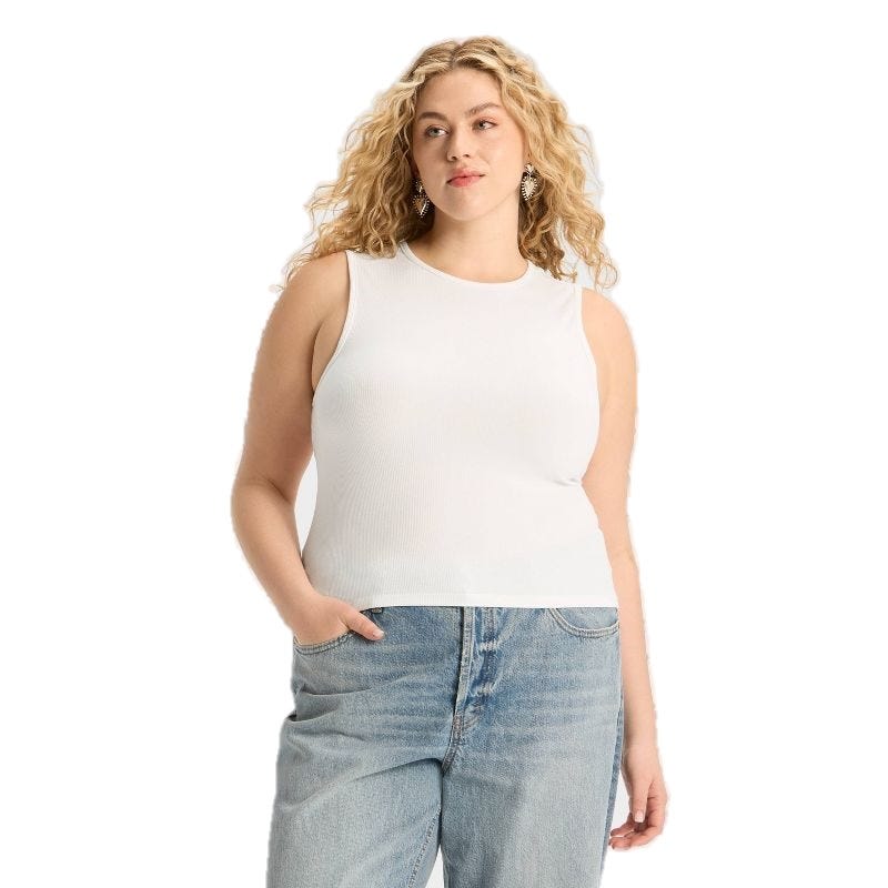 A woman in a white sleeveless top and light blue high-waisted jeans stands with one hand in her pocket against a white background.