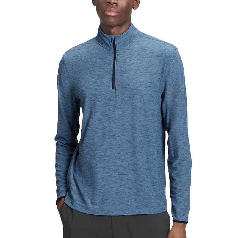 A man is wearing a blue, long-sleeved quarter-zip t-shirt with a raised collar and a textured fabric finish.