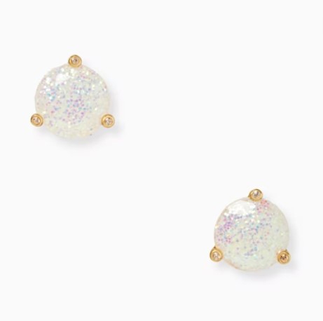 A pair of round glitter stud earrings with a translucent base and multicolored specks, each set in a four-prong gold-tone setting.