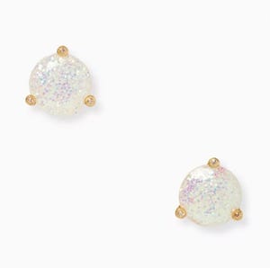 A pair of round glitter stud earrings with a translucent base and multicolored specks, each set in a four-prong gold-tone setting.