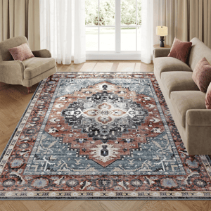 Intricately patterned rug featuring a central geometric medallion design in rust, blue, and cream tones, accented with floral motifs, perfectly complementing a neutral living room setting with beige seating and soft lighting.