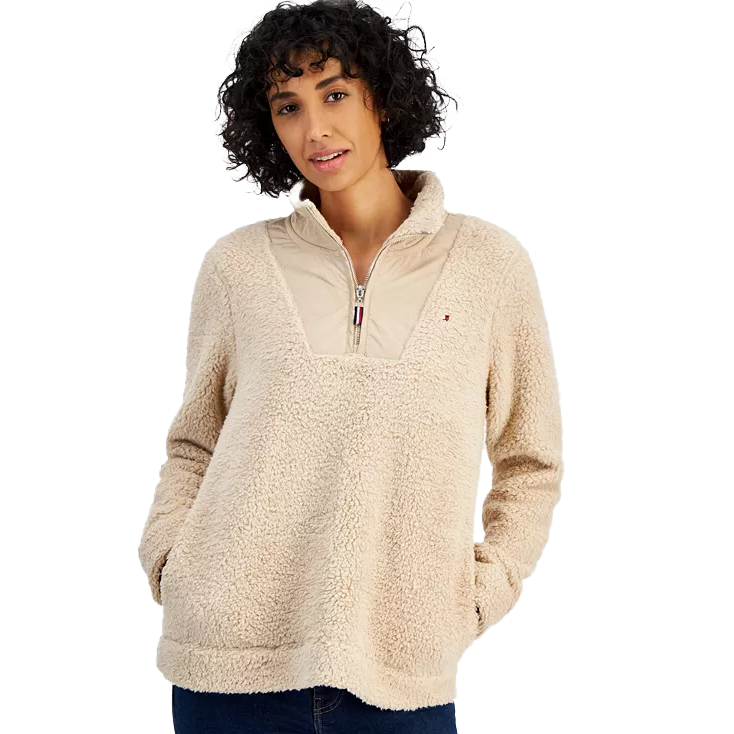 A woman wearing a beige fleece pullover with a zip neck and front pocket.