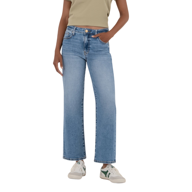 A person wearing light blue straight-leg jeans with a high waist, paired with a green cropped top and white sneakers with green accents.