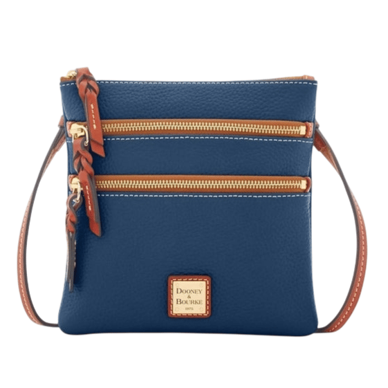 A blue crossbody bag with two front zippered pockets, featuring tan leather accents and a Dooney & Bourke label on the front.