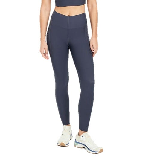 A person is wearing high-waisted, dark gray leggings paired with white athletic sneakers. The outfit includes a matching cropped top.