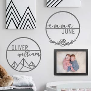 Wall art including personalized name signs and one framed photograph of two babies.