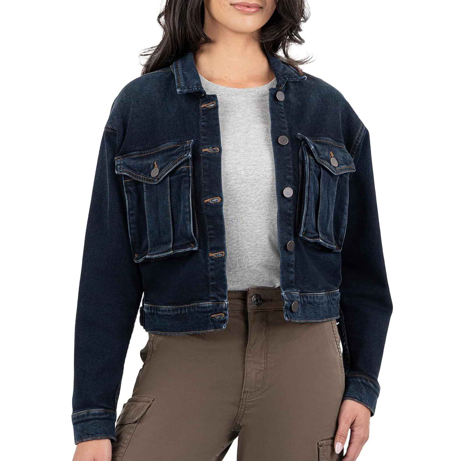A cropped dark denim jacket with button closure, two large front flap pockets, and subtle distressing, paired with a light gray T-shirt and khaki cargo pants.