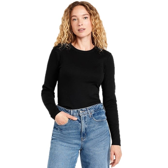 A person wearing a black long-sleeve top and blue jeans with one hand in a pocket.