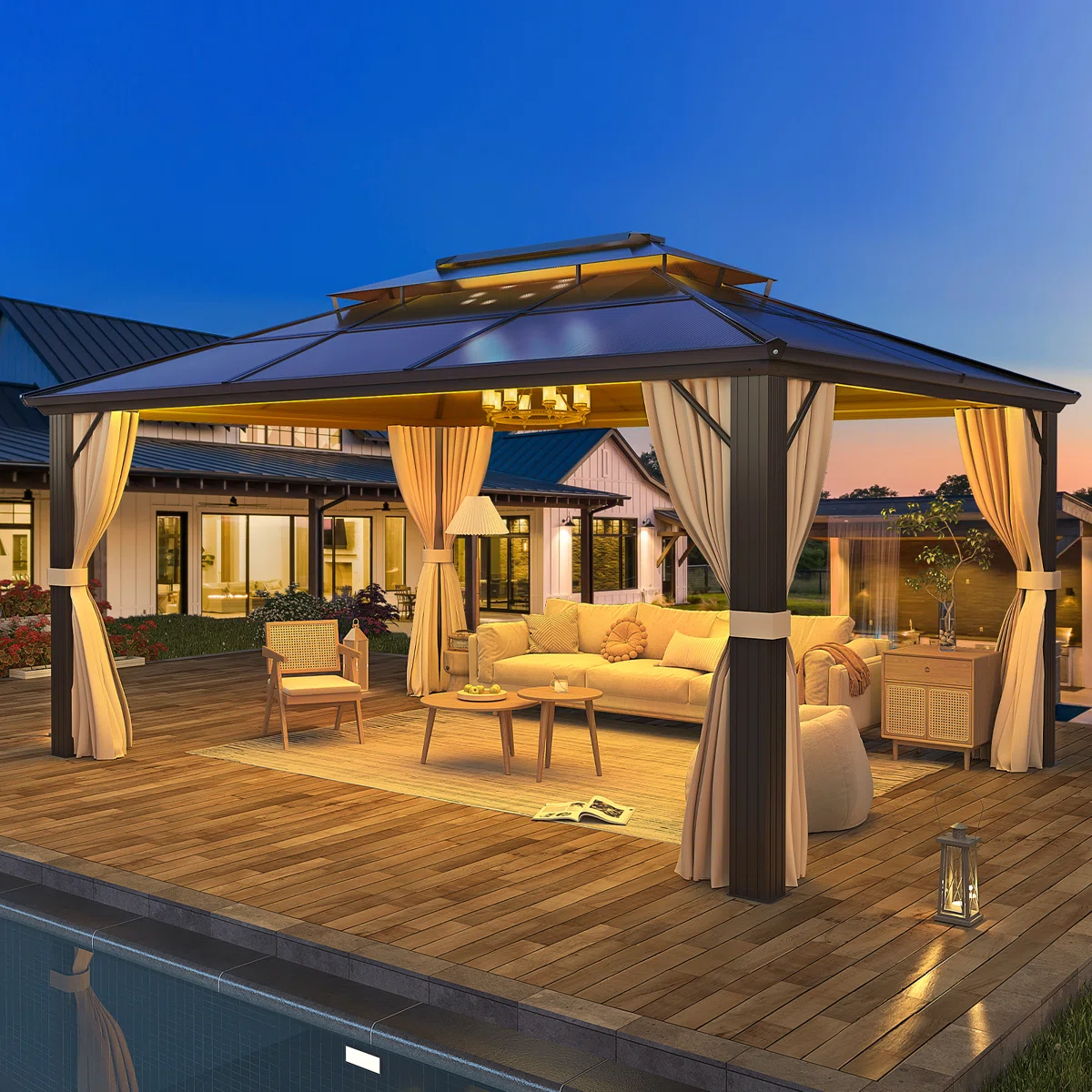 A spacious gazebo with a dark metal frame and cream curtains houses outdoor furniture, including a sofa, chair, and tables, on a wooden deck near a pool, with soft lighting creating a cozy atmosphere.