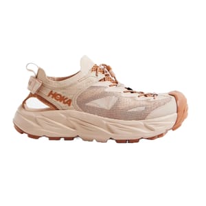 Hoka Women's Hiking Shoes in beige feature a mesh upper, open-back design, chunky sole, and prominent toe guard, offering both style and functionality for trail experiences.