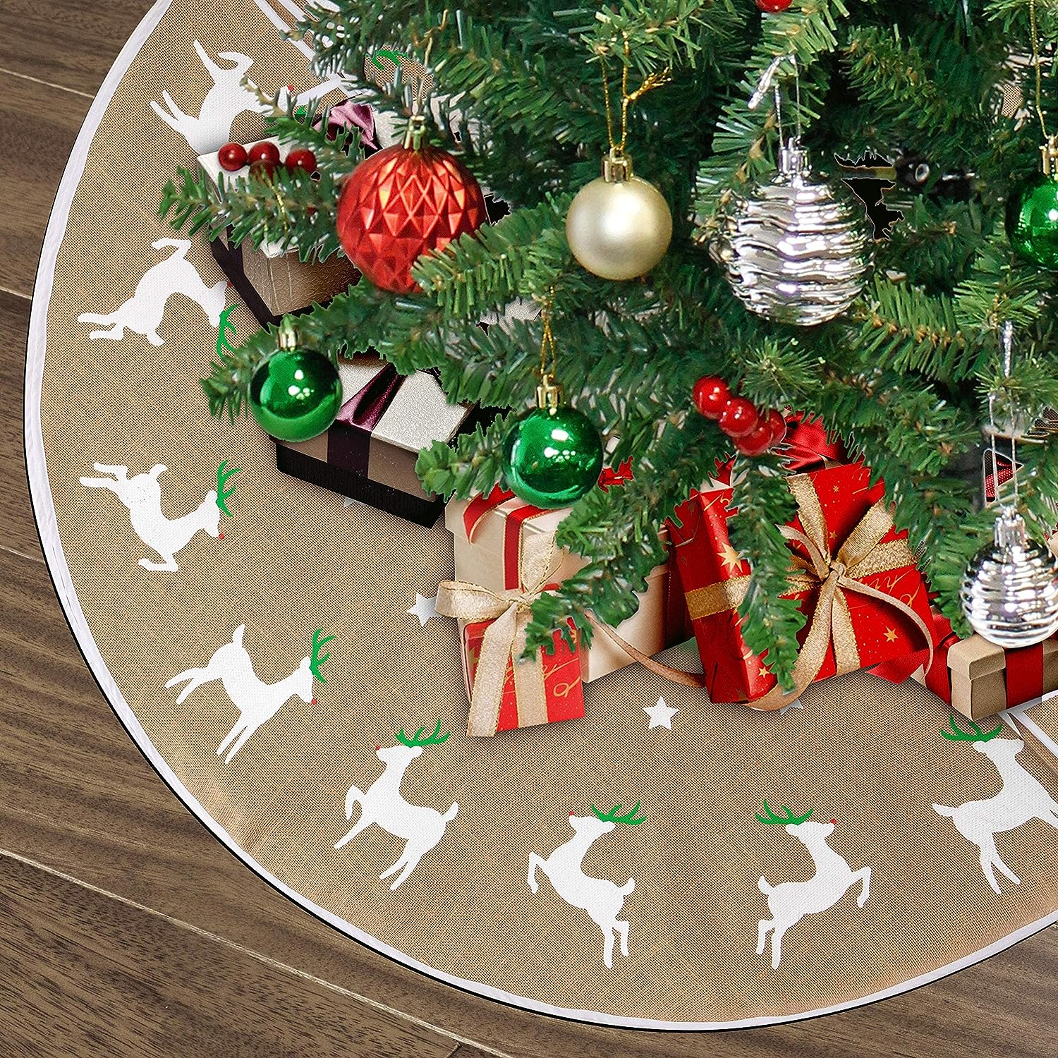 A circular tree skirt with reindeer motifs around the border, placed under a Christmas tree decorated with red and green ornaments and presents.