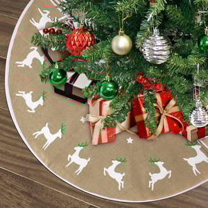 A circular tree skirt with reindeer motifs around the border, placed under a Christmas tree decorated with red and green ornaments and presents.