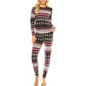 A person is wearing a cozy set of festive long-sleeve pajamas with a reindeer and snowflake pattern in black, white, red, and gray tones.